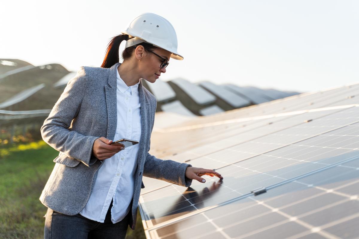 Eine Fachfrau begutachtet Solarpanels einer PV-Anlage.