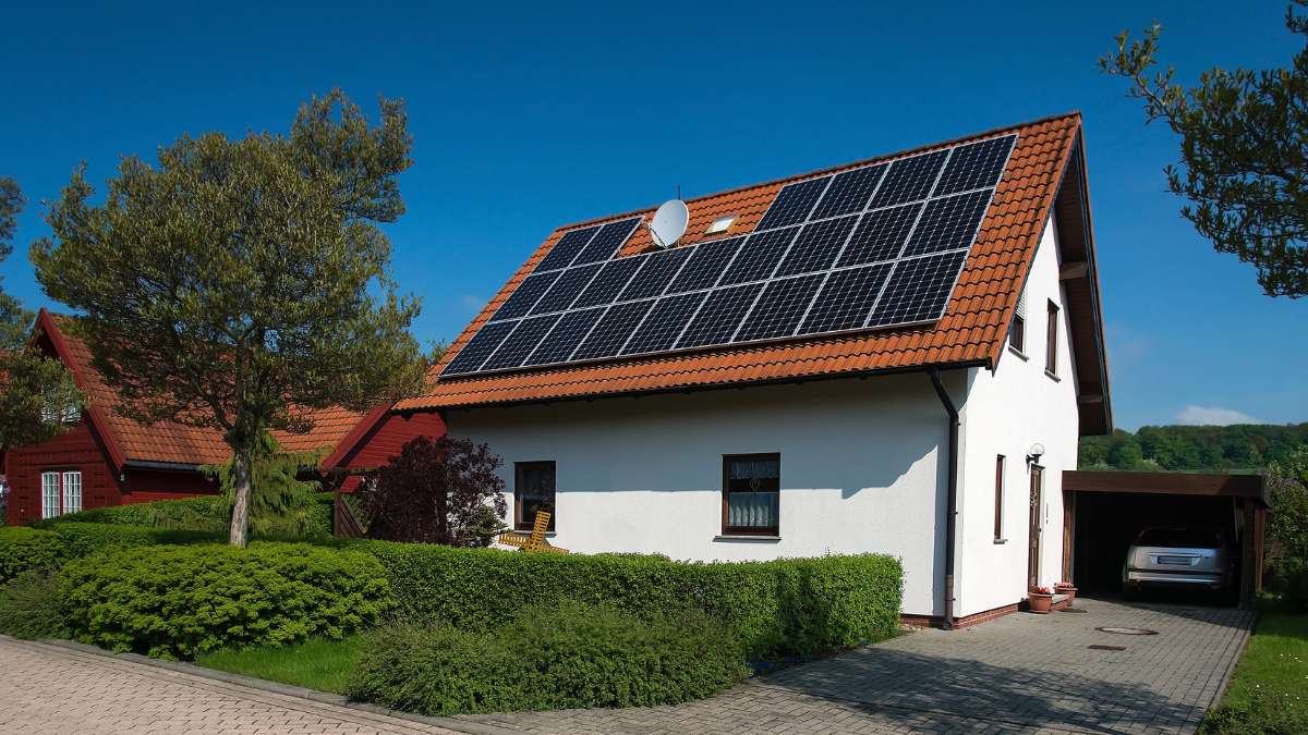 Ansicht auf ein weißes Haus mit Solarpanels auf dem Dach