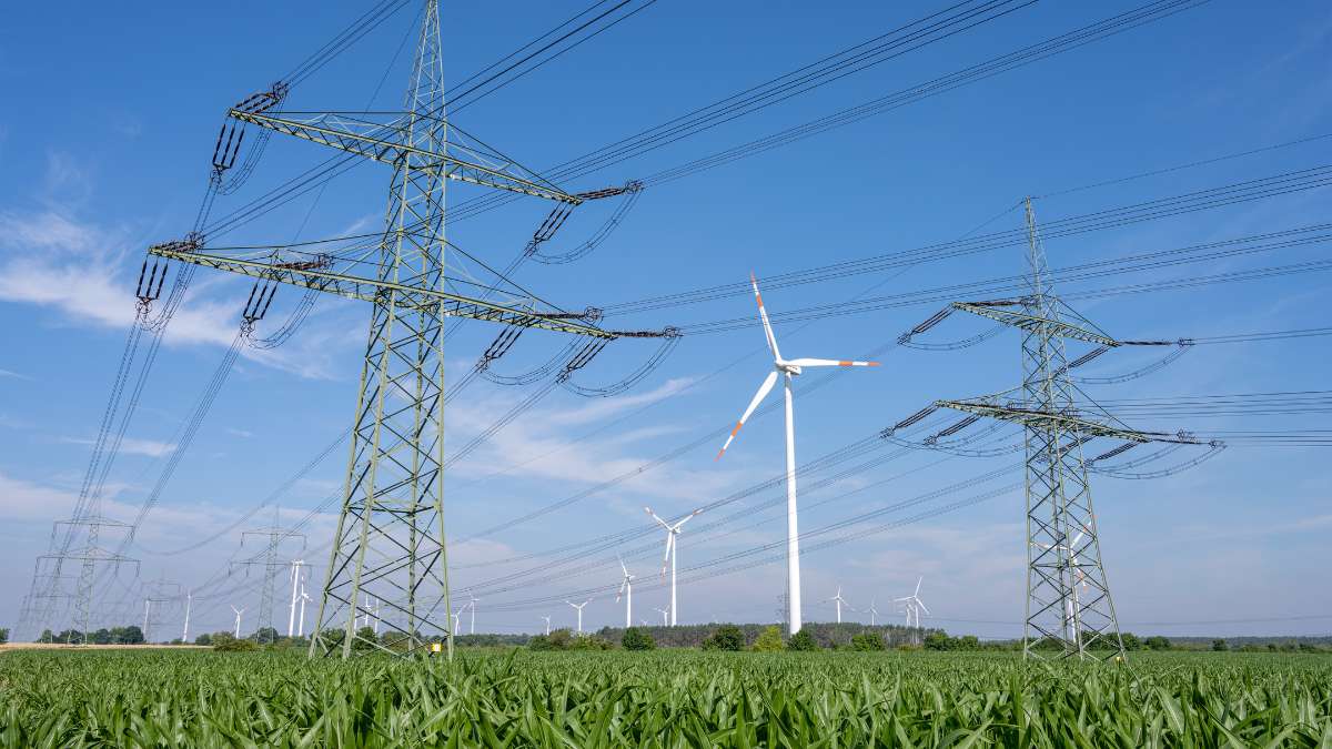 Strommasten und Windkraftanlagen auf einem Feld